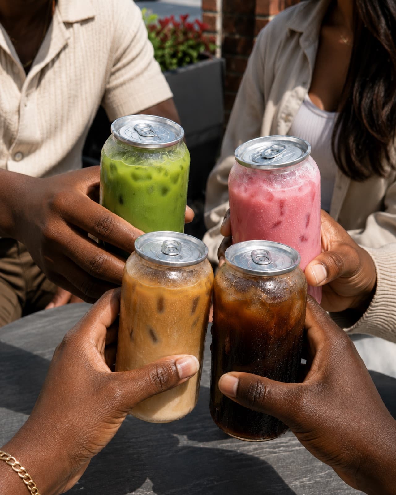 Four friends toasting clear cans of matcha, strawberry, latte, and cold brew on a patio